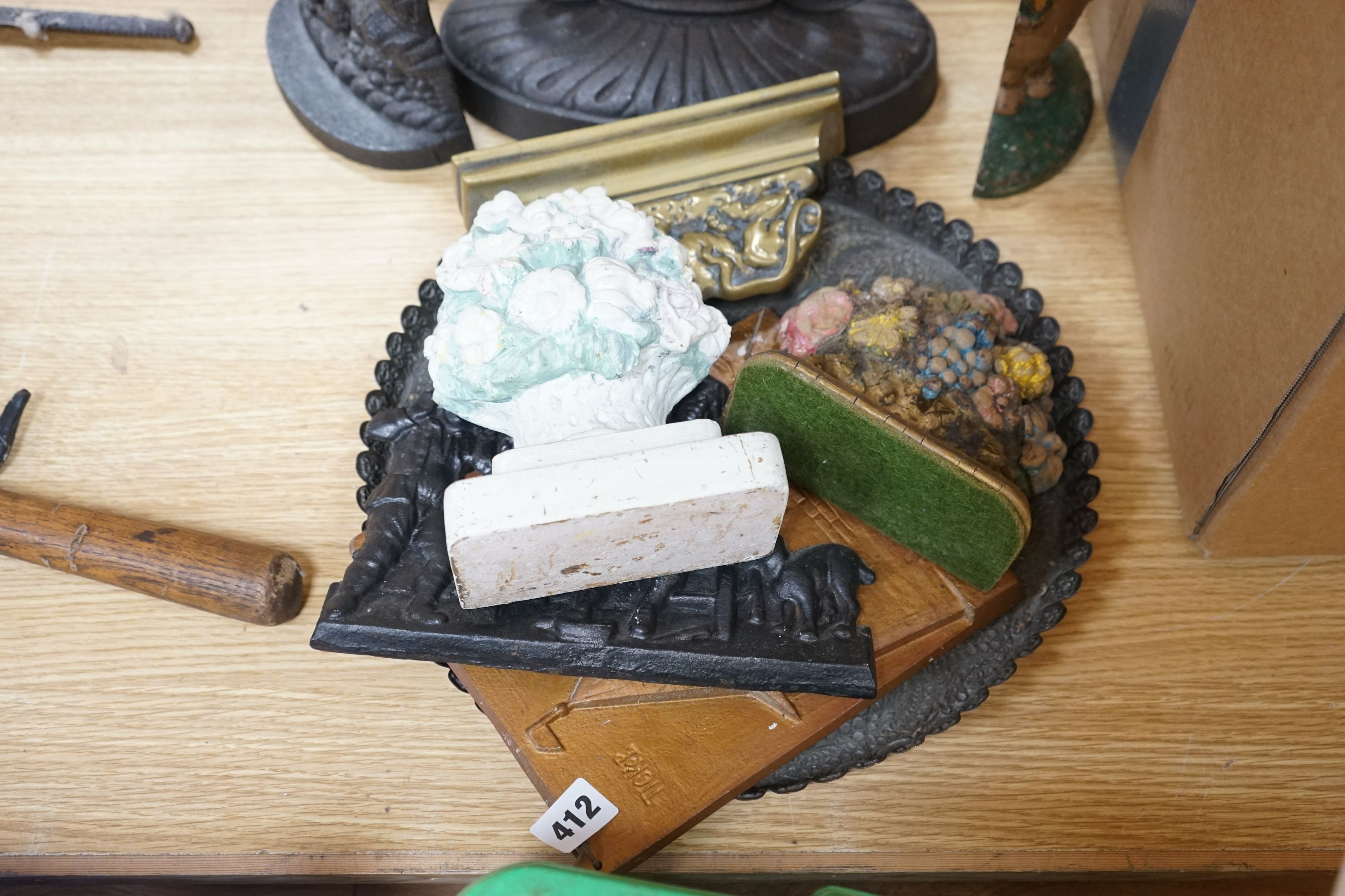 Eight cast iron door stops, a brass lion, a tray, two panels and two floral plaster models, (13)